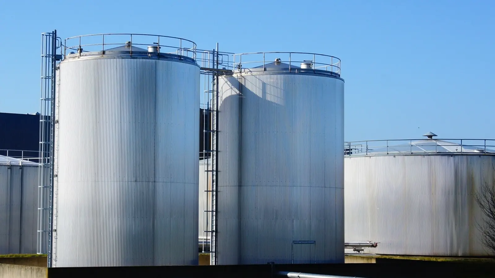 Stainless steel storage silos under a blue sky