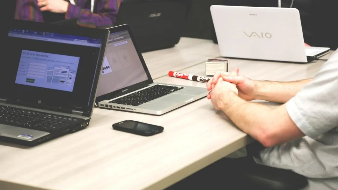 Team working at a shared desk with several laptops