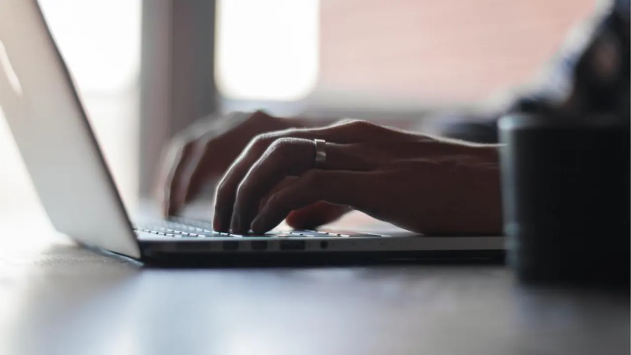 Hands typing on a laptop