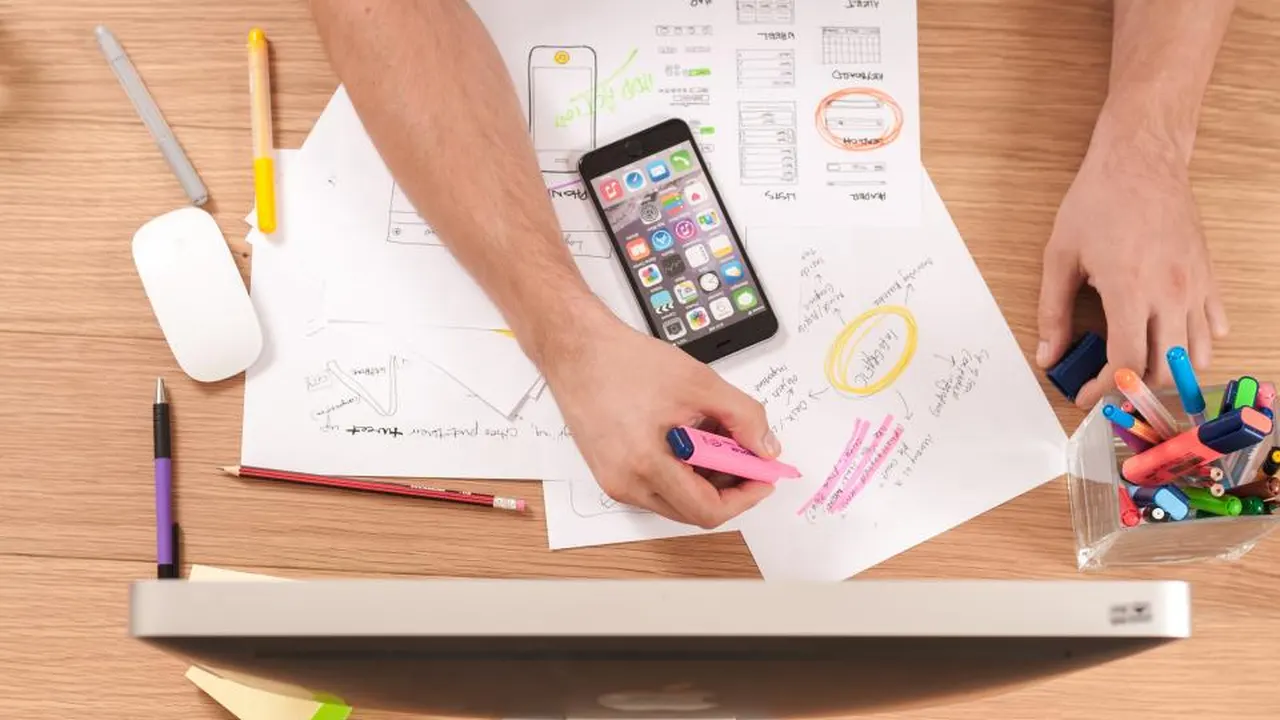 App wireframes and a phone on a desk